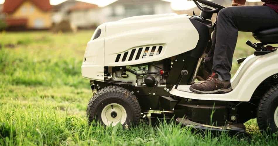 white riding lawn mower cutting grass