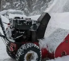 A red snowblower in use blowing snow
