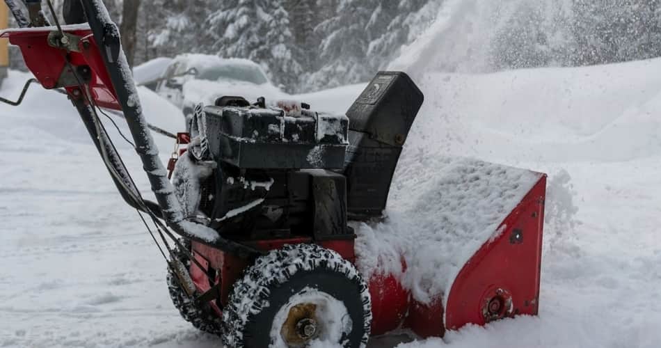 A red snowblower blowing snow